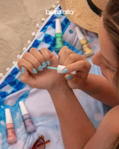 Mulher aplicando esmalte azul claro da coleção Dolce Verão Beira Alta Cosméticos
