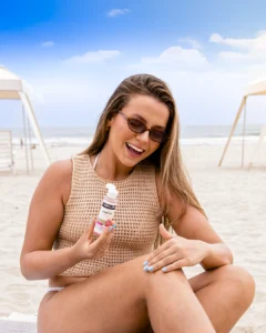 Mulher aplicando produto corporal após banho de lua na praia